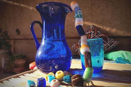 Intérieur de maison en pisé. Table en feuilles de palmier, étui décoratif et vaisselle en verre recyclé 