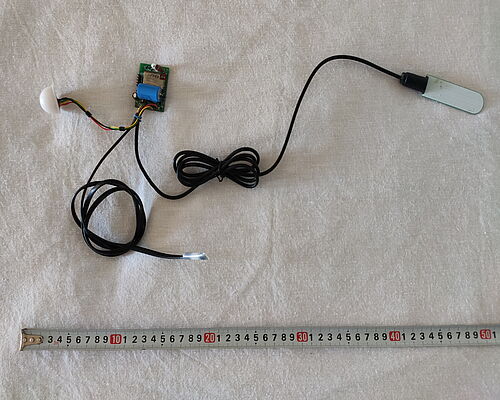 Electronic filling of the climate sensor. Central on the top is a board with a battery and a transmitting antenna, on the right side is a soil moisture sensor, on the left side — a light sensor. 
Below in the center is a remote (in this assembly) temperature sensor